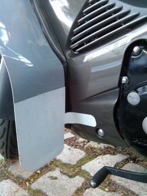 Lasche aus dem gleichen Kunststoff, zwischen den umgefalteten unteren Teil eingeklebt, mit Heißluft abgewinkelt und dann mit 3M VHB an die Verkleidung gebappt.